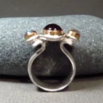 geschwungener, barock anmutender Granatring mit einen tiefrotem Granatcabochon und zwei Labradorithen in Rosecut Schliff, gefasst in 750er Roségold