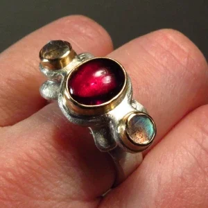 geschwungener, barock anmutender Granatring mit einen tiefrotem Granatcabochon und zwei Labradorithen in Rosecut Schliff, gefasst in 750er Roségold